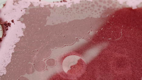 una gota de agua cae sobre una superficie roja brillante