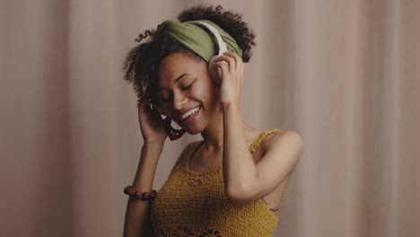 joven afroamericana positiva escuchando música con auriculares inalámbricos, bailando y riendo, en cámara lenta