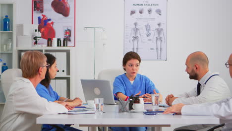 nurse sitting at conference desk explaining to team about research informations