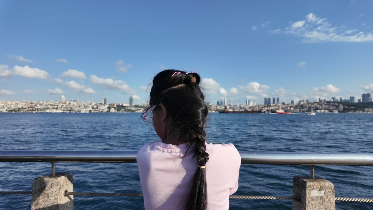 A person views the distant city skyline over the water