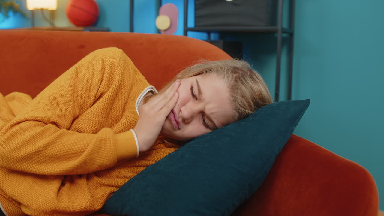 niño adolescente con dolor de dientes sosteniendo la mejilla sufriendo un dolor insoportable haciendo caras en el sofá en casa