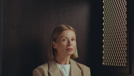 portrait of mature woman sitting in confessional booth