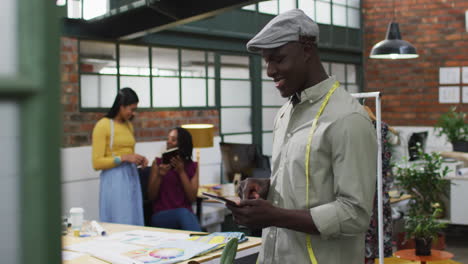 portrait of happy african american male fashion designer wearing tape measure at office