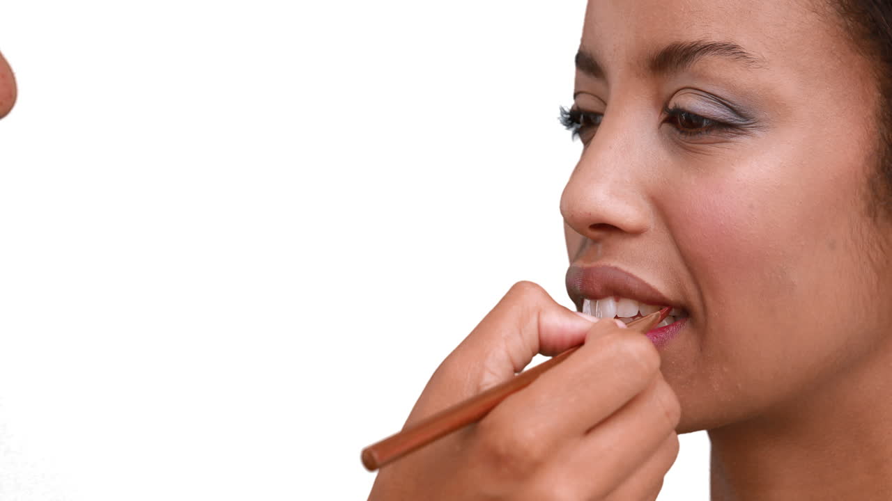 Make up artist putting lip gloss on models face