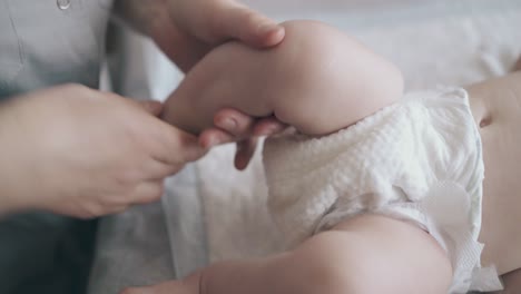 professional and skilled nurse massages newborn baby legs