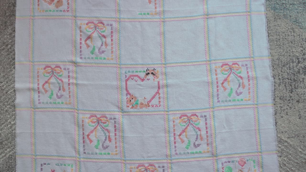 Slow pullout revealing shot of a cross-stitched baby blanket on the ground