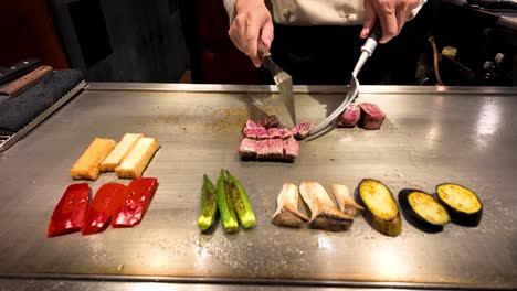 chef cooks wagyu beef and vegetables on a hot plate in osaka, japan