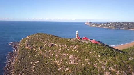 Wunderschöne-Insel-Mit-Einem-Leuchtturm-Auf-Einem-Hügel-Mit-Blick-Auf-Zwei-Strände-Und-Eine-Luftaufnahme-Des-Ozeans-An-Einem-Klaren,-Sonnigen-Tag