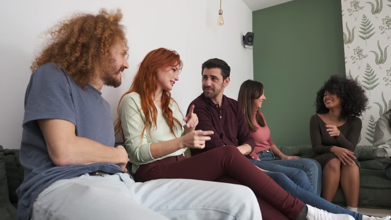 Happy woman gossiping with male friends sitting on couch at home