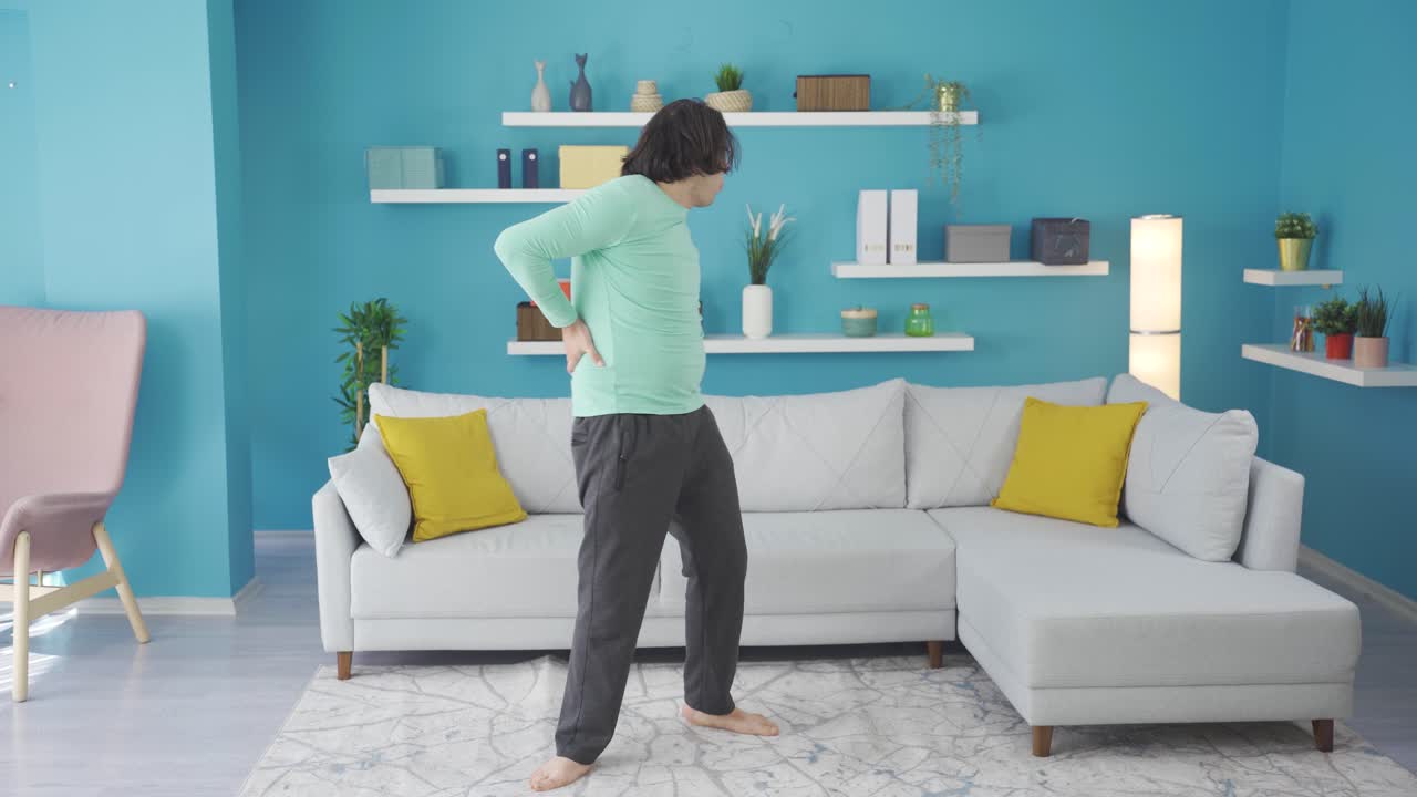 el hombre gracioso se duele la espalda mientras hace ejercicio en casa.