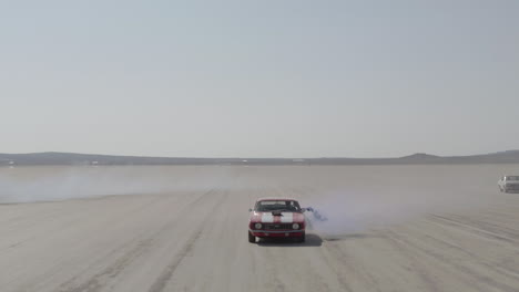 aerial shot of multiple muscle cars traveling through the desert holding flares