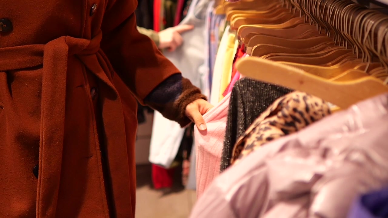 Cliente che sfoglia vestiti su una gruccia in un negozio al dettaglio.