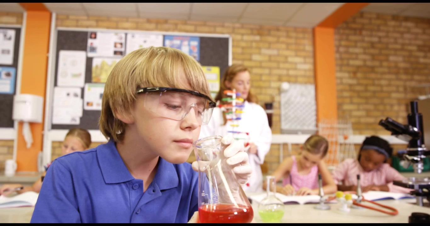 Ragazzo preadolescente che solleva una beuta di Erlenmeyer, causando una sovrapposizione di codice e testando una soluzione rossa in un laboratorio scientifico.