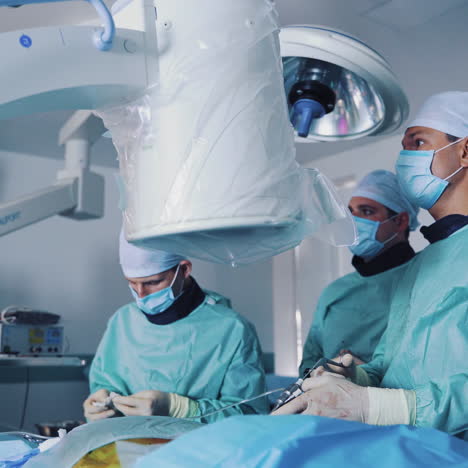 surgeons perform an operation to a patient in clinic. specialists in medical uniform use modern technologies during the operation.