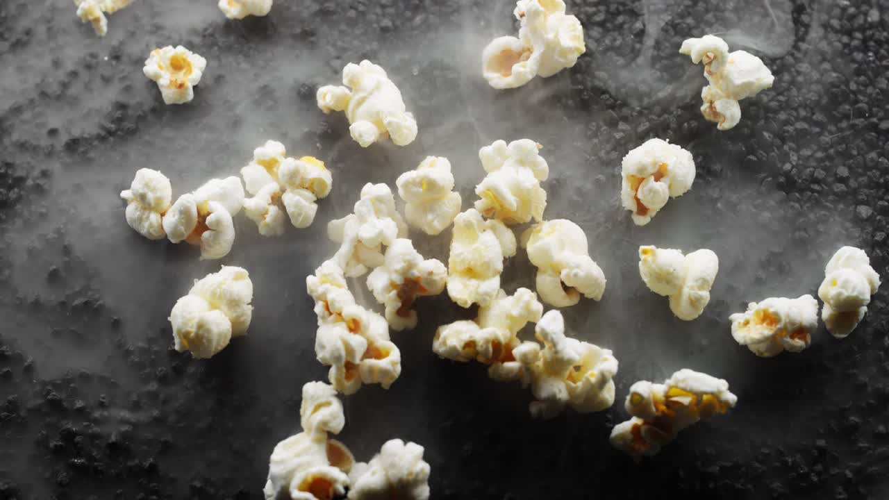 Popcorn fresco al burro giace su un letto di rocce nere incandescenti.