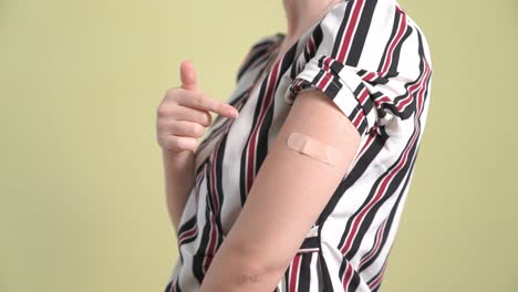 young woman showing covid-19 vaccine bandage merrily