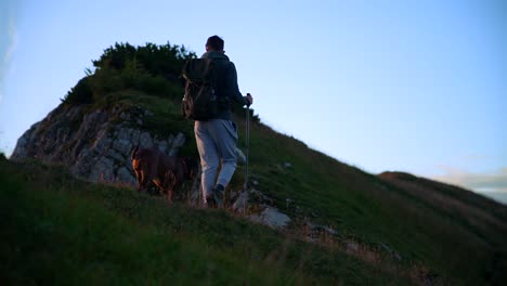 forward movement with a camera on a gimbal filmed in 4k with a man and hiking on top of a mountain at sunrise in the slovenian mountains in the alps, with beautiful clear skies