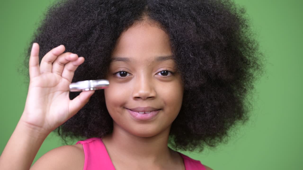 joven chica africana con cabello afro jugando con el girador inquietante