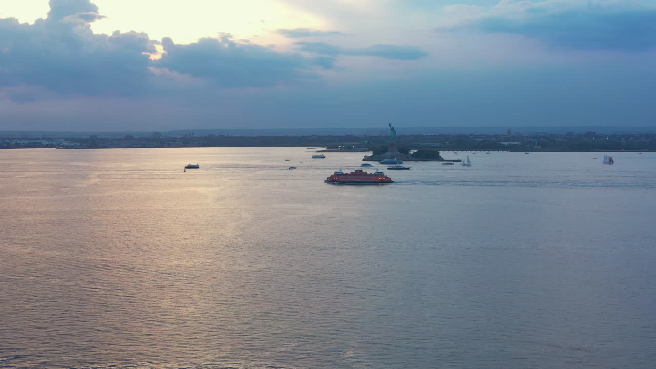 zoom de inclinación ascendente aéreo del puerto de nueva york con el ferry de staten island y la estatua de la libertad al atardecer espectacular