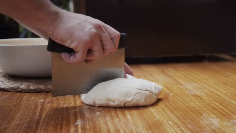 Chef-splits-the-pizza-dough-into-parts-on-a-wooden-table