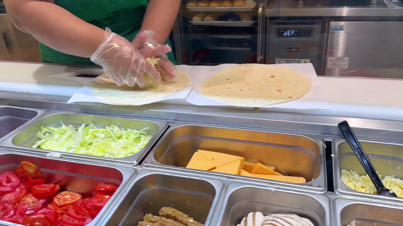 Primo piano di un lavoratore con i guanti che prepara un involtino fresco di verdure a Bangkok.