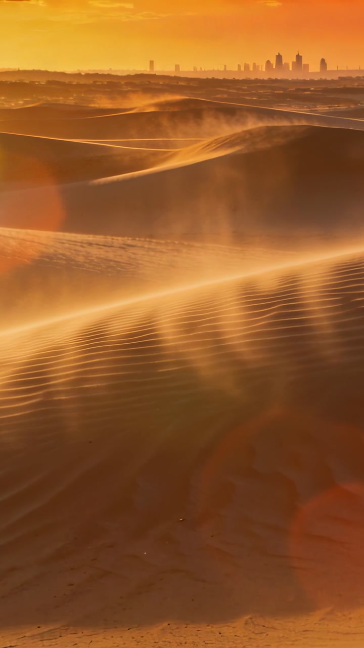 Vertical video: Wind lifting sand plumes, main dune showing rippled ridges and warm glow for travel