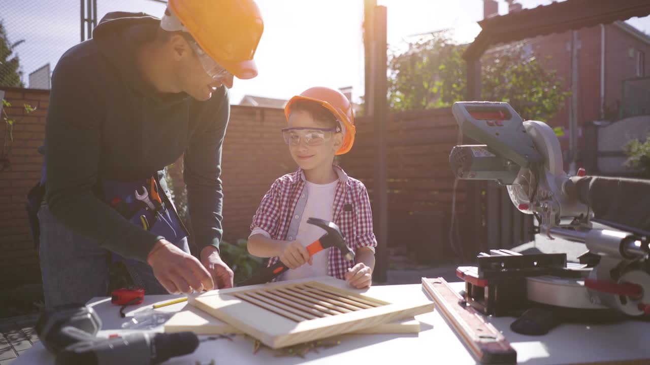 el padre enseñando a su hijo pequeño a usar martillo y clavos