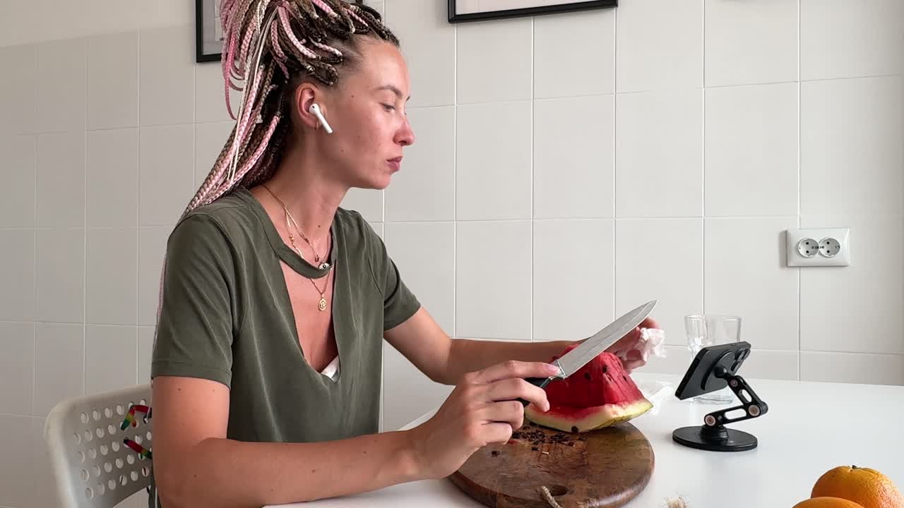 Young Woman Cutting and Eating Watermelon in Kitchen