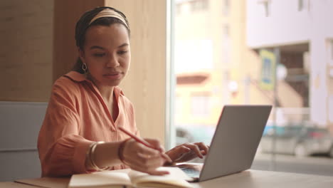 female freelancer working on laptop in cafe