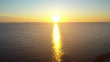 beautiful ocean sun set aerial drone footage of bright sun touching horizon and casting reflection of light across water