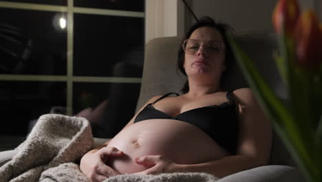 pregnant woman resting on couch at home, night, comfort with soft blanket