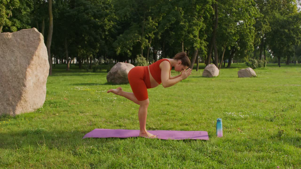 mujer embarazada practicando yoga en un parque