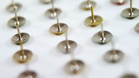 Golden-push-pin-arranged-on-white-background-4k