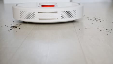 robot vacuum cleaner with red lamp drives to scattered trash