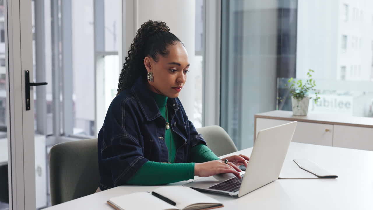 Businesswoman working at desk in office with laptop and phone