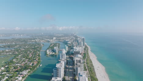 Luxurious-apartment-buildings-on-Miami-Beach.-Aerial-ascending-shot-of-urban-borough-along-sandy-sea-coast-with-turquoise-water.-Miami,-USA