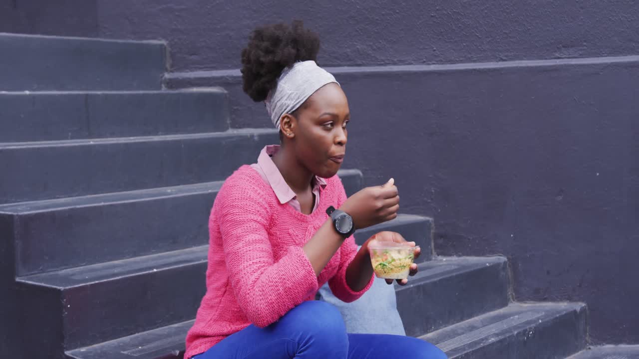African american eating a salad in street
