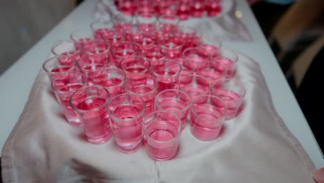 tray of small pink shot glasses arranged on a white cloth, ready for serving.