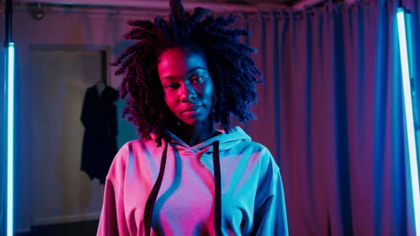 portrait of a young woman bathed in neon pink and blue lights