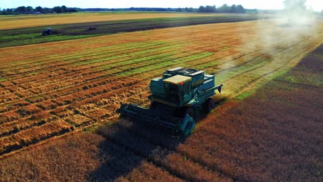 combine harvester working in an agricultural field during harvest in lithuania - aerial drone shot