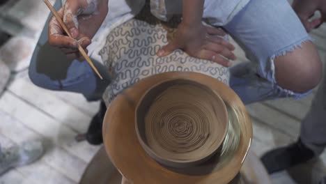 person shaping clay on pottery wheel