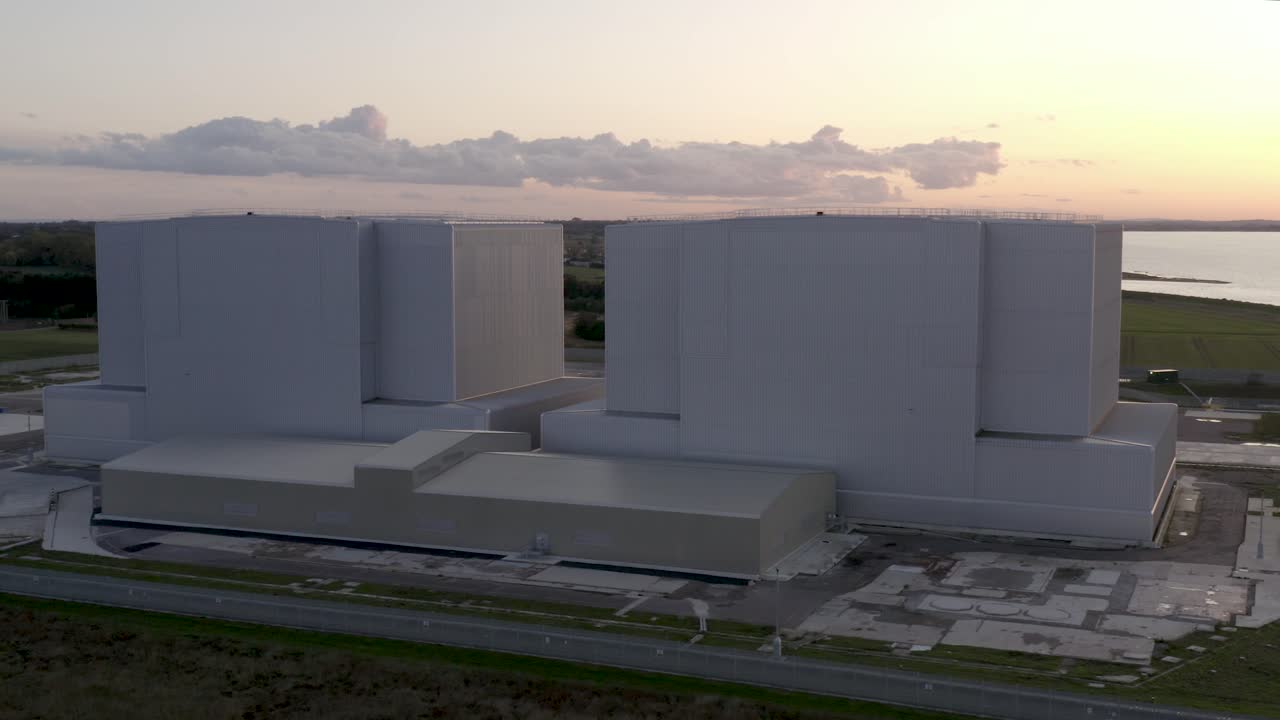 Centrale nucleare di Bradwell-on-Sea con tramonto rosa e dorato, nuvole e fiume