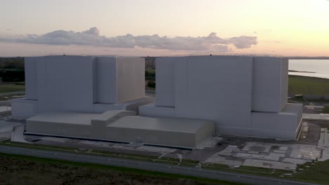 Bradwell-on-Sea-nuclear-power-station-with-pink-and-gold-sunset,-clouds-and-river