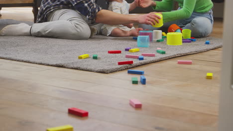 Transgender-Family-With-Baby-Playing-Game-With-Colourful-Toys-In-Lounge-At-Home