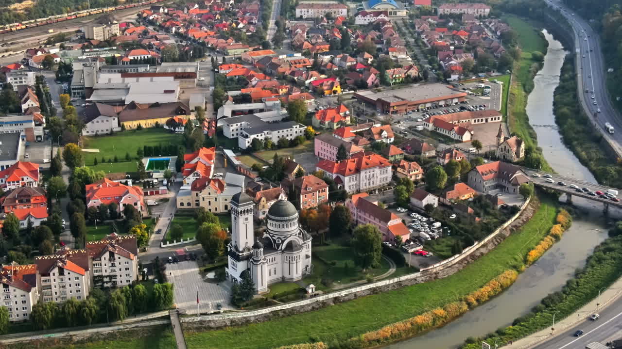 Aerial drone view of Sighisoara, Romania. Old buildings, Holy Trinity Church, streets with greenery, cars, river