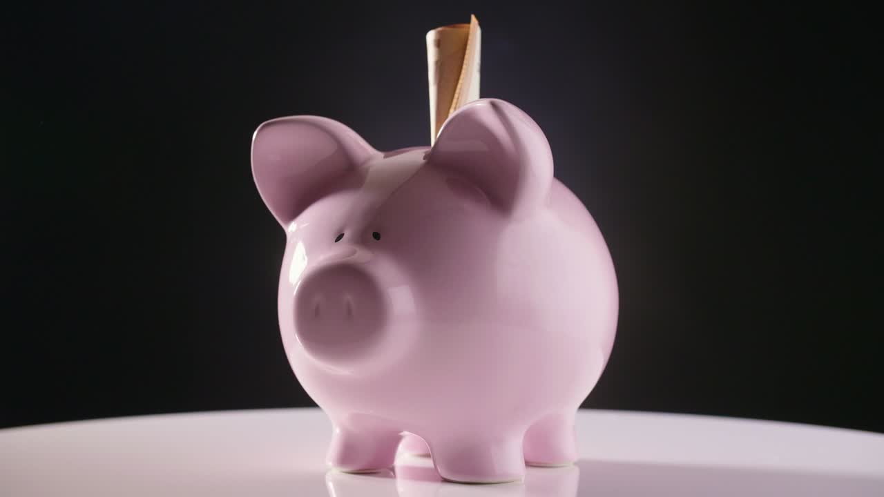 piggybank con la moneda girando en la mesa