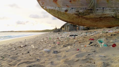 Concepto-De-Contaminación-De-Basura-Marina,-Basura-De-Bolsas-De-Plástico-En-Una-Playa-De-Arena-Tropical-Con-Puesta-De-Sol-En-El-Mar-En-El-Fondo-Y-Un-Barco-De-Pescadores-De-Madera-En-África