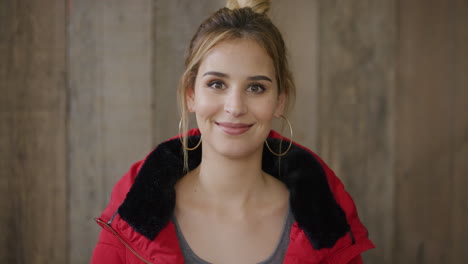 Retrato-De-Una-Joven-Elegante-Y-Sonriente,-Una-Mujer-Caucásica-Disfrutando-De-Un-Estilo-De-Vida-Feliz-Con-Una-Chaqueta-Roja-Y-Fondo-De-Madera