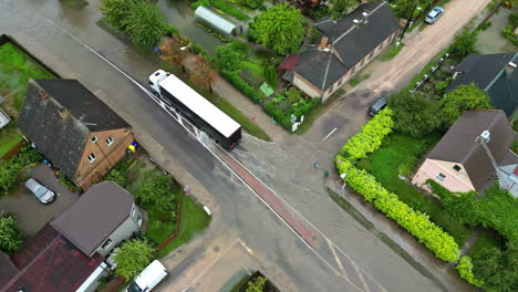 drone fly tracks transport truck in flooded street, quiet neighborhood daylight