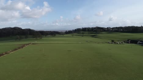 drone flight over ulverston across pasture fields towards hills providing an aerial view of an empty meadow.
